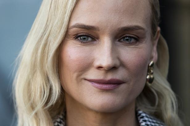 Nahaufnahme von Diane Kruger mit blonden, gewellten Haaren und goldenen Ohrringen.