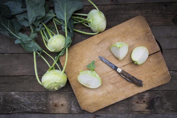 Organic kohlrabi on wood, knife on chopping board, halved - Stock-Fotografie