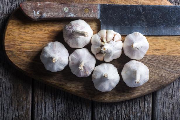 Garlic on wooden chopping board. - Stock-Fotografie