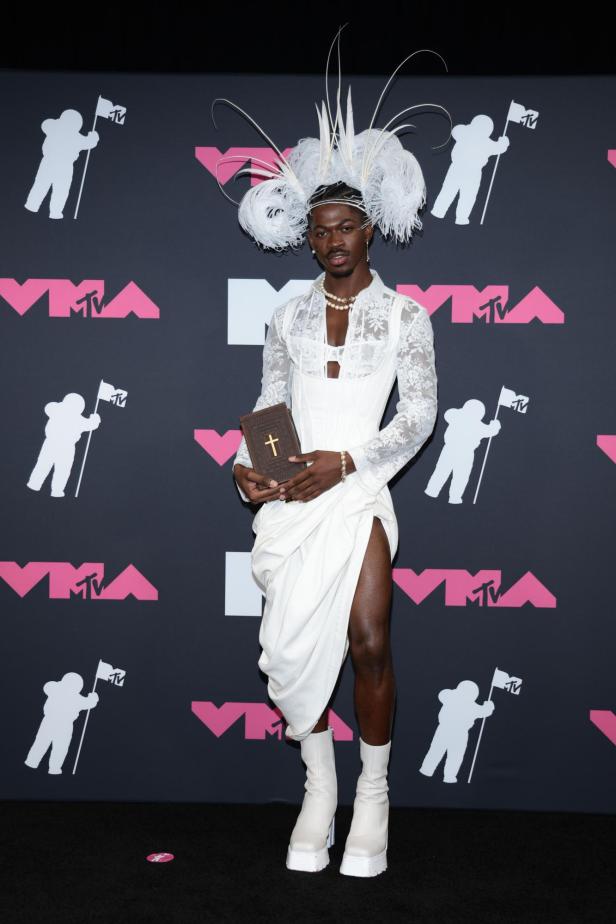 Lil Nas X auf den VMAs trägt weißes gerafftes Kleid mit großem Kopfschmuck und einer Bibel in der Hand