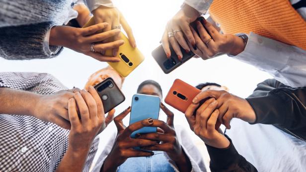 Jugendliche stehen im Kreis und halten Smartphones in der Hand