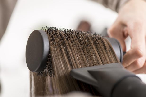 Haare werden mit einer Rundbürste geföhnt.