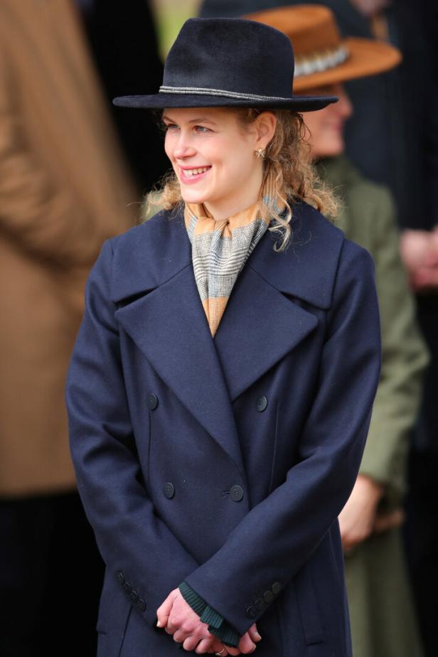 Lady Louise Windsor mit Hut und blauem Mantel lächelt.