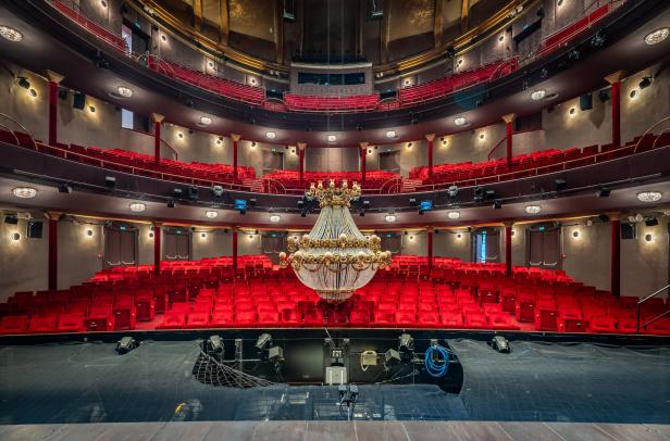 Blick in ein leeres Theater mit rotem Samt und einem Kronleuchter, wie im „Phantom der Oper“.