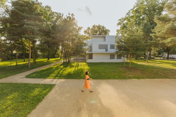 Frau spaziert an Haus vorbei, Architektur