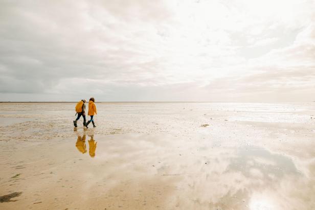 Frau und Mann spazieren im Wattenmeer