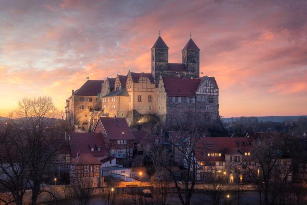 Mittelalterliches Schloss erhebt sich majestätisch auf einem Hügel bei Sonnenuntergang, der Himmel ist ro