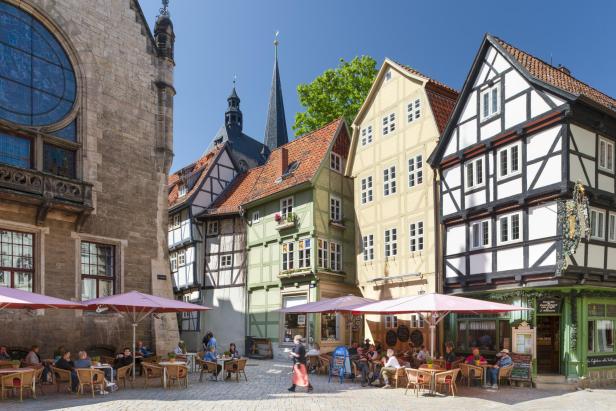 Belebter Marktplatz in mittelalterlicher Stadt mit Fachwerkhäusern und Cafés