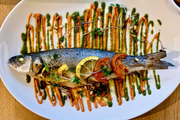 Fisch auf einem Teller mit roter und grüner Sauce