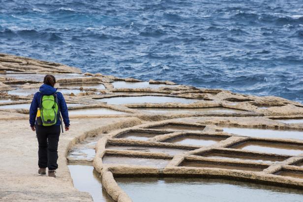 Salzpfanen Gozo, Frau mit Rucksack steht an der Küste