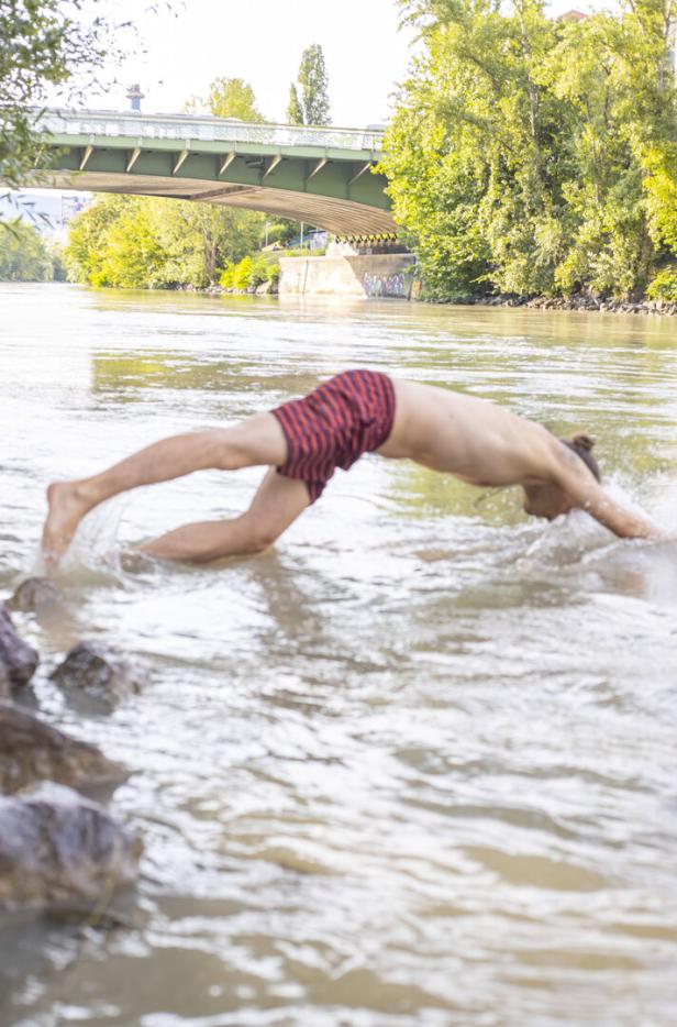 Ein junger Mann köpfelt von der Einstiegsstelle aus ins Wasser