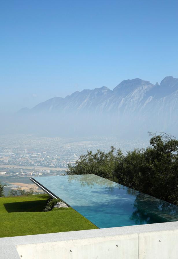 Von der Terrasse hebt sich ein Infinity-Pool ab, im Hintergrund stehen Berge, darunter liegt eine Wüstenstadt