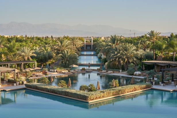 Eine gigantische Pool-Landschaft, bestehend aus mehreren Becken. Rundherum sind liegen und viele Palmen.