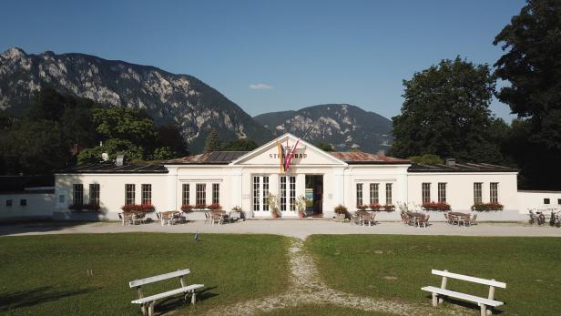 Ein mondänes Eingangsgebäude mit Flaggen. Dahinter erheben sich die Berge der Wiener Alpen.