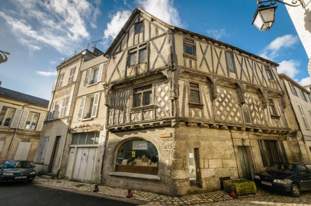 Ein sehr altes Fachwerkhaus mit Kalkstein-Elementen an einer Straßenecke in der Stadt Cognac