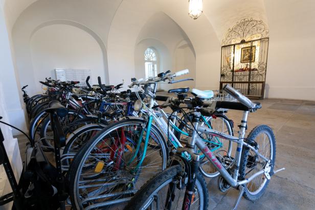 Ein weißer Eingangsbereich mit Fahrradabstellplatz und einem alten Altar, der sich hinter einem Gitter befindet.