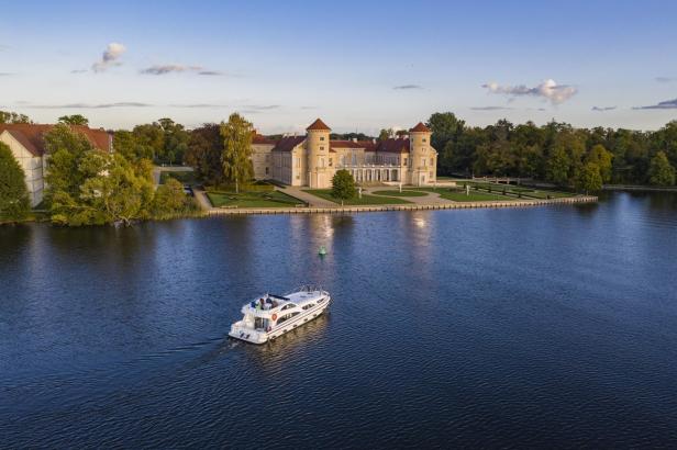 Ein Hausboot befindet sich auf einem See vor einem Schloss