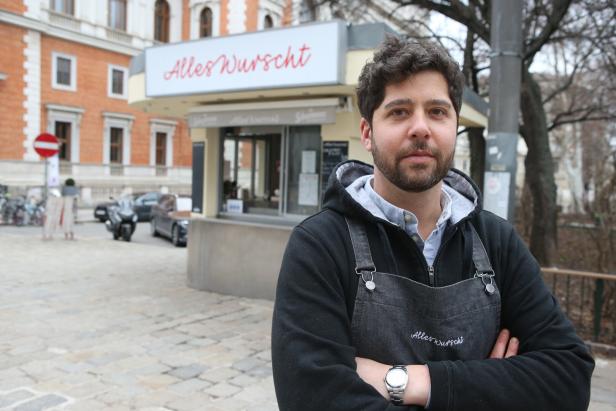 Der Würstelstand-Besitzer Sebastian Neuschler steht am Börseplatz, hinter ihm sein Stand, wo er Bosna verkauft.