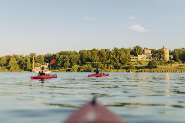 Kajakfahren auf dem See mit einem Schloss im Hintergrund, das eine malerische Landschaft bietet.