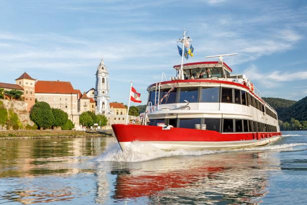 Ein Schiff auf der Donau vor einer Burg in Dürnstein, Wachau, Österreich.