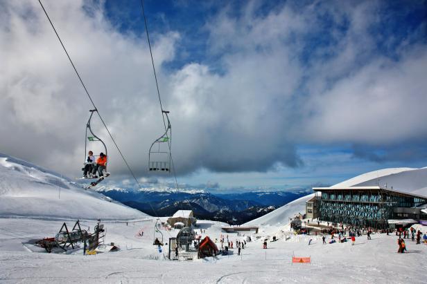 Ein Sessellift im Gebirge mit einem Panoramarestaurant daneben