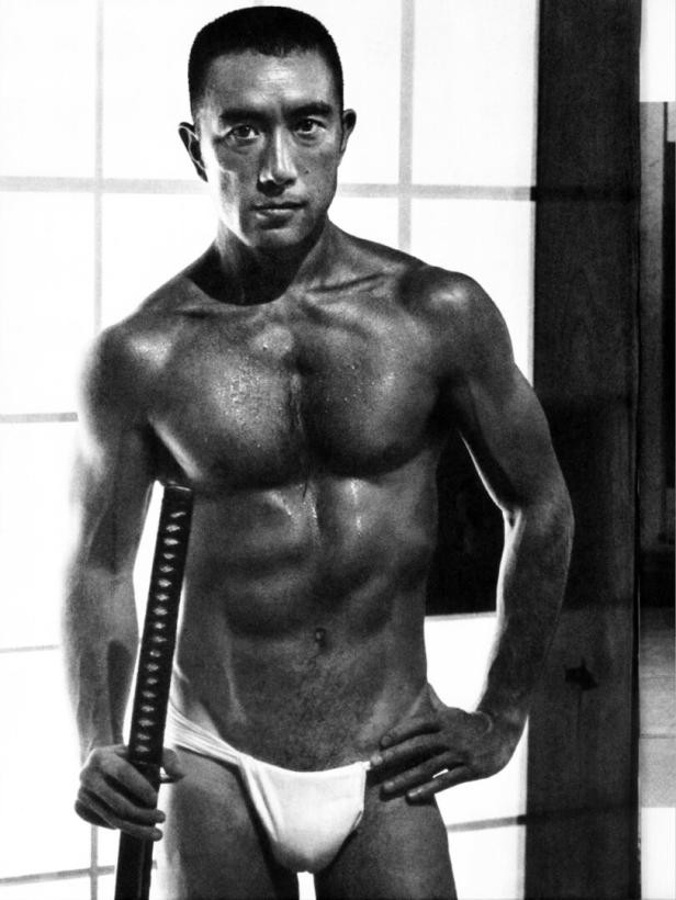 Yukio Mishima nur mit einem Slip gekleidet, muskulös und ein Samuraischwert in der Hand