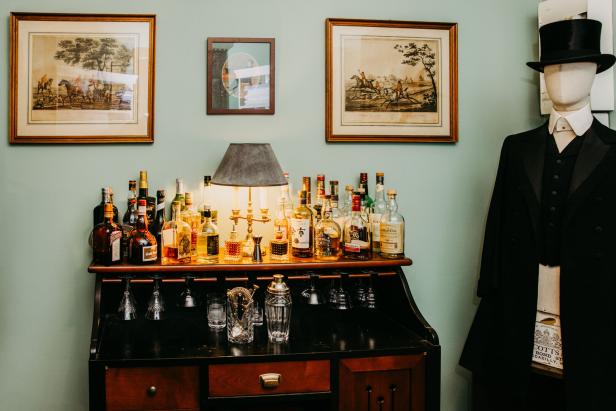 Maß-Salon Possanner Eine gut bestückte Bar auf einem Sekretär. An der Wand hängen englische Jagdbilder