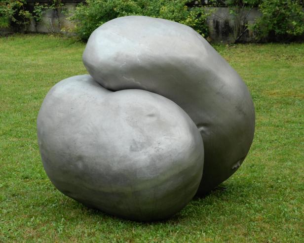 Metallskulpturen auf einer Wiese, die sich umarmen. 