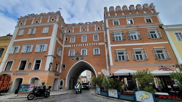 Ein orangenes Haus, das über eine Straße führt und wie eine Art Burg oben endet. 