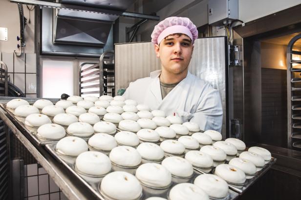 Ein Mitarbeiter in Hygienekleidung präsentiert die Eismarillenknödeln auf einem großen Tablett, bevor sie in den Schockfrostraum  kommen.
