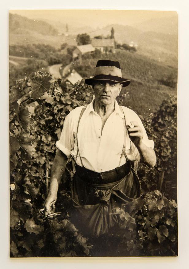 Sepiafoto eines Winzers mit Hut und Hosenträgern bei der Weinlese im südsteirischen Hügelland.