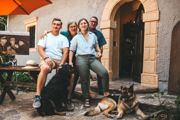 Familie Jakopé-Barthau mit zwei Hunden vor dem Eingang der Kästenburg.