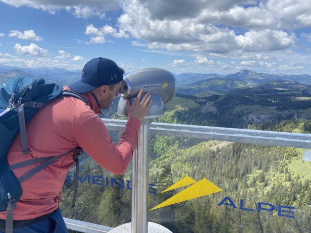 Ein Mann schaut durch ein Fernrohr und beobachtet die umliegenden Berge.