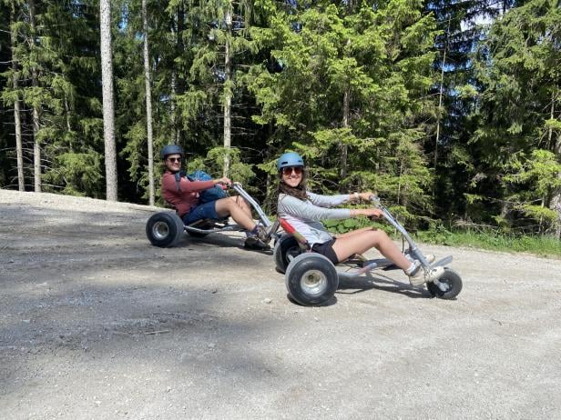 Zwei Personen fahren in einem Mountaincart durch den Wald.