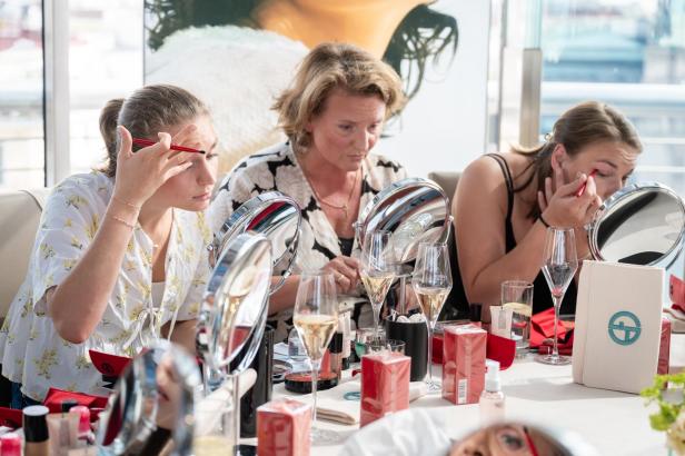 Frauen bei einem Beauty-Workshop sitzen an einem Tisch und verwenden Make-up für ihre Anwendungen.