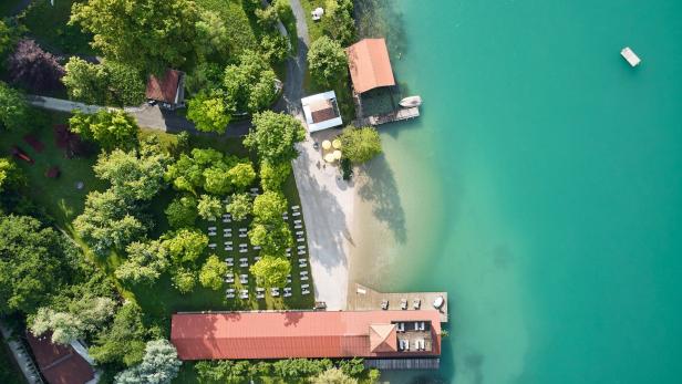 Blick von oben auf den Strand des Hotels Karnerhof und das Wasser des Faaker Sees.
