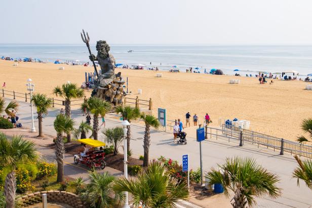 Blick auf den Strand von Virginia Beach mit der Neptunstatue und vielen Menschen.