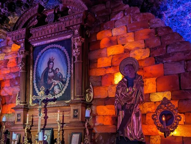 Eine Madonnenikone und eine Heiligenstatue in einem Raum mit Ziegelwänden.