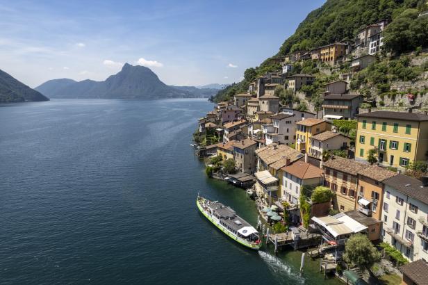 Ein Ausflugsschiff fährt auf dem Luganersee entlang der Küste von Gandria.