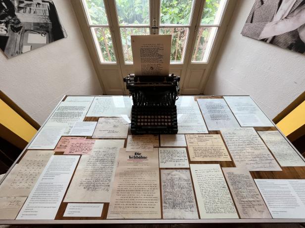 Eine alte Schreibmaschine steht auf einem Tisch voller Dokumente.