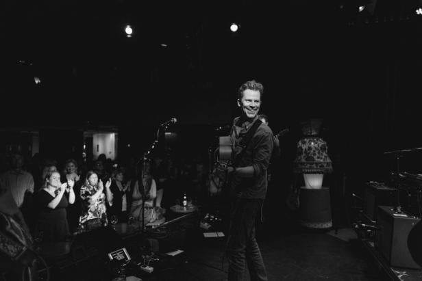 Der Musiker mit Gitarre in der Hand, unten stehen die Fans