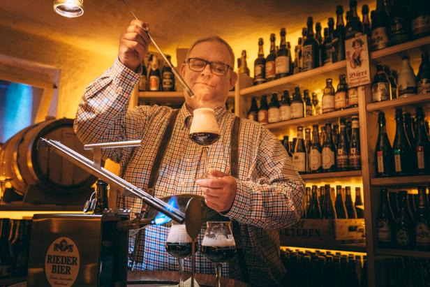 Der Wirt taucht einen heißen Metallstab ins Bier.