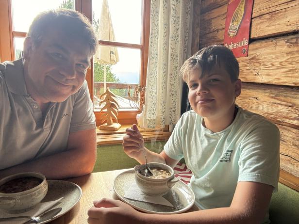 Vater und Kind essen Fritattensuppe auf einer Berghütte