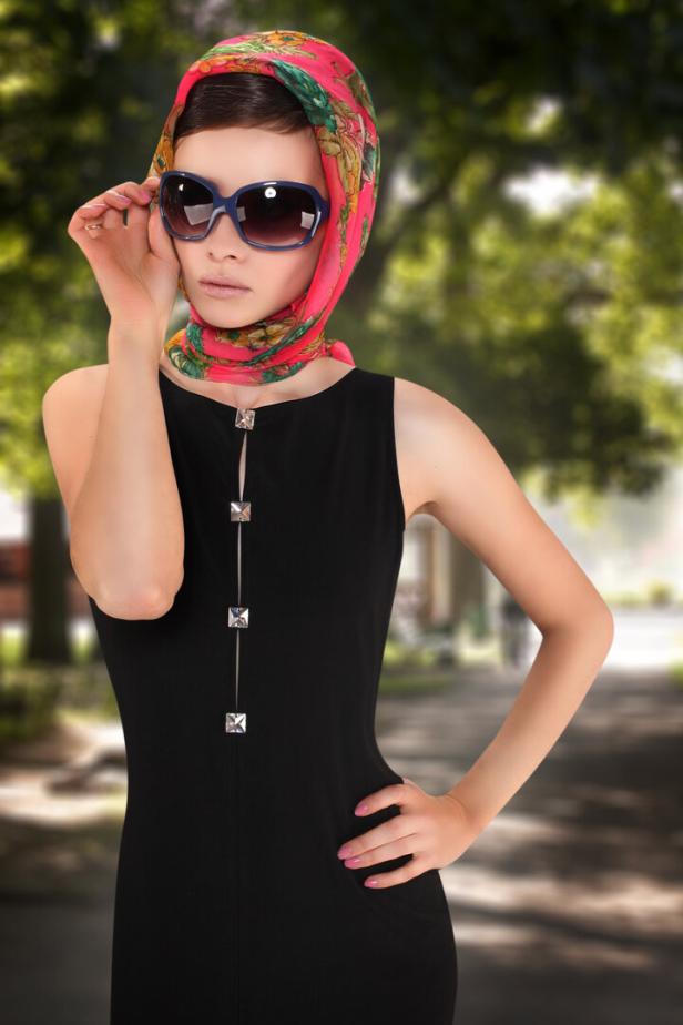 Eine junge Frau im schwarzen Kleid trägt ein Tuch im 1950er-Stil