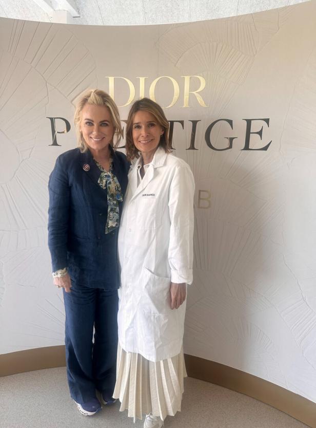 Zwei Frauen posieren vor einer Wand mit dem Dior Schriftzug.