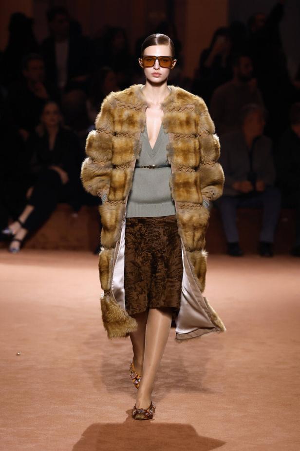 Ein Model präsentiert einen Pelzmantel, einen grauen Pullover und einen braunen Rock auf dem Laufsteg der Fendi Herbst/Winter Kollektion 2025/26.