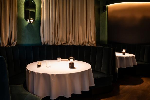 Ein gedeckter Tisch in einem eleganten Restaurant mit grünen Samtbänken.