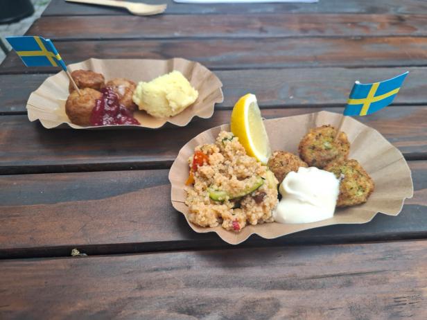 Zwei Speisen auf Papptellern, die ab Jänner 2026 bei Ikea neu am Speiseplan stehen: Falafel (im Vordergrund) mit Couscous, Gemüse und Aioli und Fleisch-und-Gemüse-Bällchen mit Erdäpfelpüree, Rahmsauce und Preiselbeeren