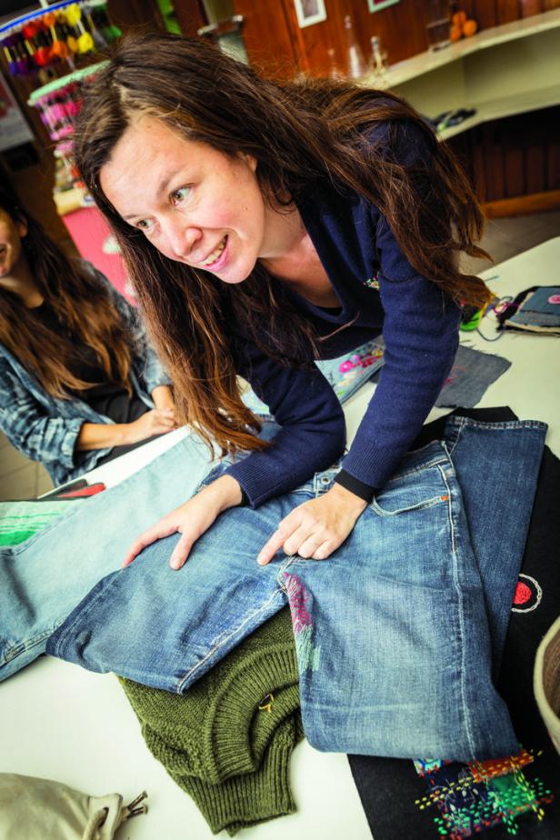 Eine Frau zeigt auf eine Jeans mit Stickereien, während eine andere Frau zusieht.