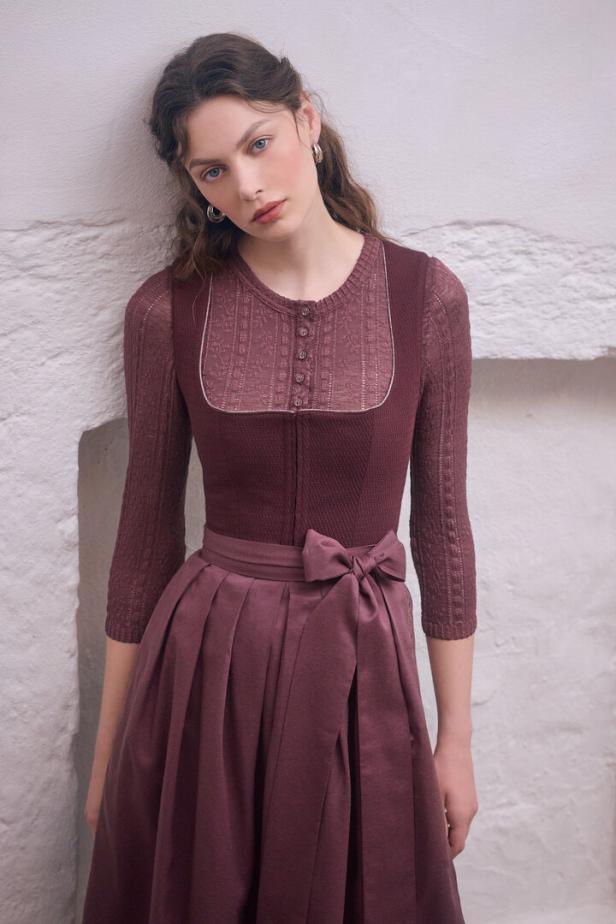 Eine junge Frau in einem Dirndl-ähnlichen Kleid mit einer Schleife um die Taille.